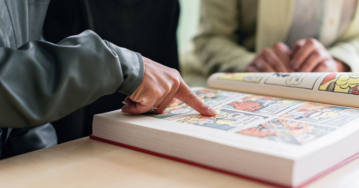 Two individuals focus on reading a colorful comic book, highlighting engaging stories.