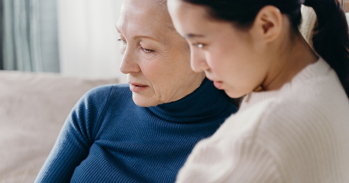 A loving bond between an elderly woman and a younger adult indoors.