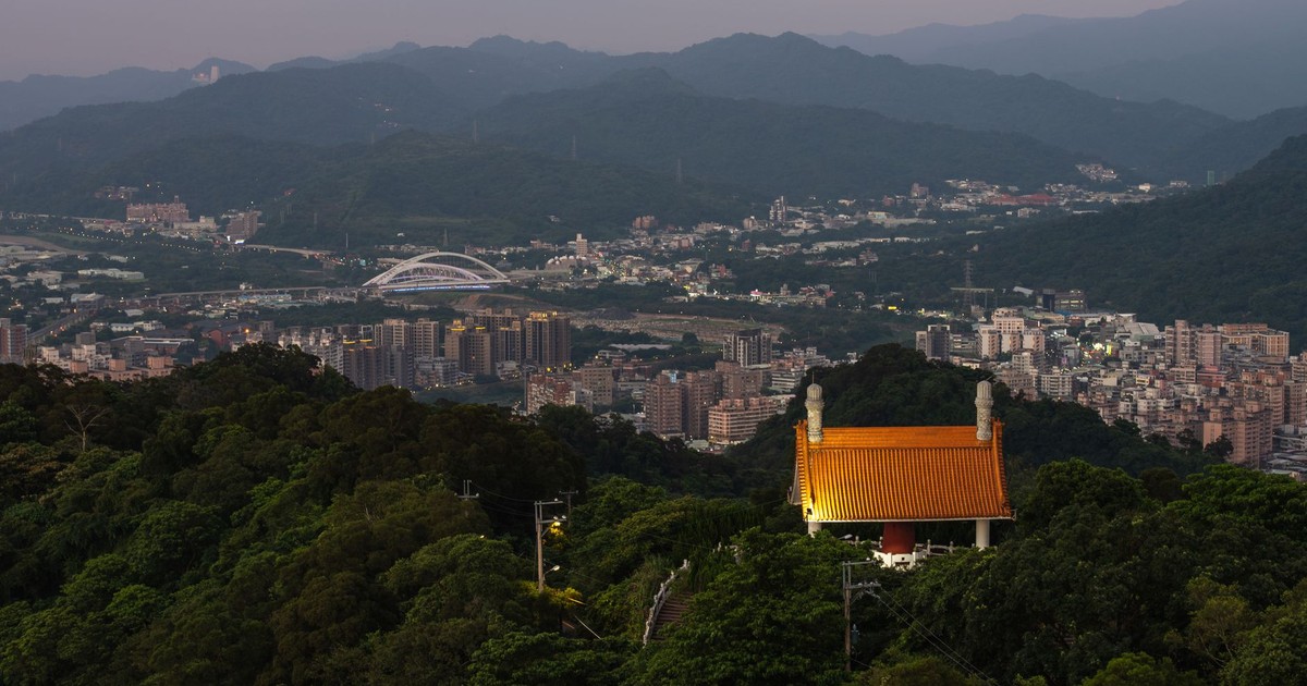 Overlooking Sanxia District with a temple roof amidst lush greenery during twilight.