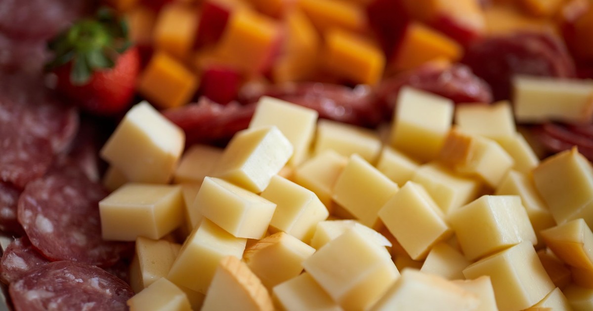 Close-up of assorted cheeses and salami on a gourmet platter with strawberries.