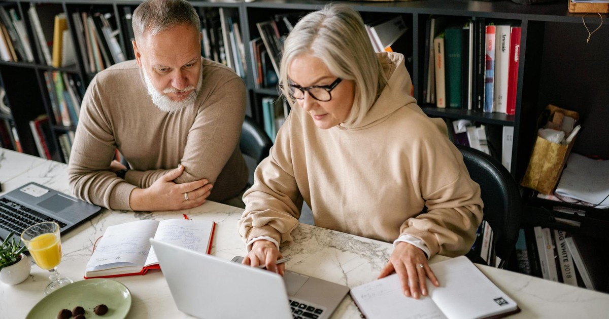 Elderly couple collaborating on laptops in a cozy home office setting.