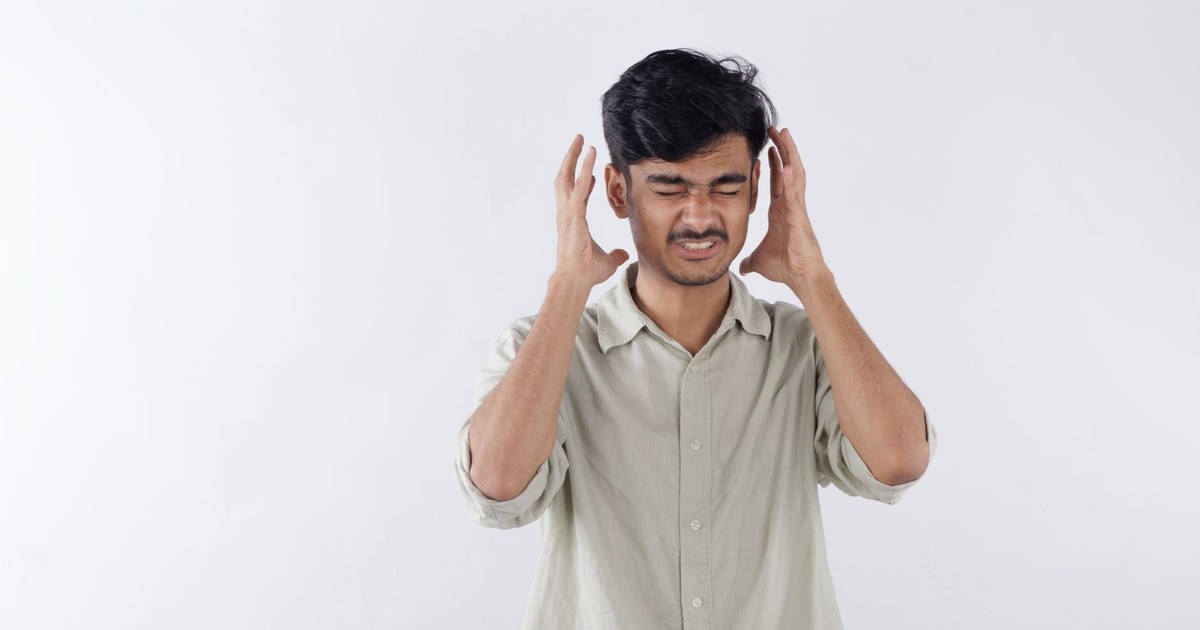 Young man expressing frustration, hands on head, isolated background.