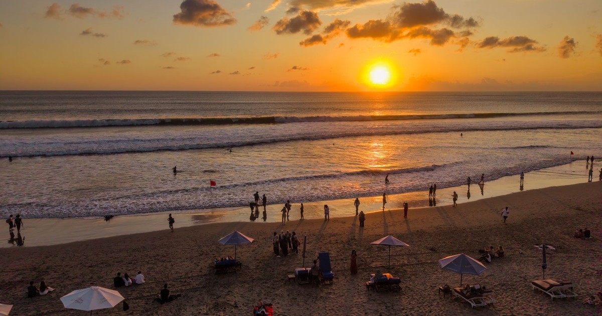 People enjoying a vibrant sunset at Kuta Beach, Bali. Perfect for travel and leisure themes.