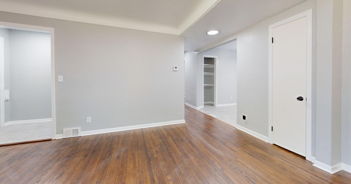 Bright empty room with wooden floor, perfect for real estate listings.