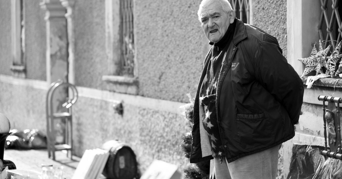 A senior man browsing an outdoor antiques market on a sunny day.