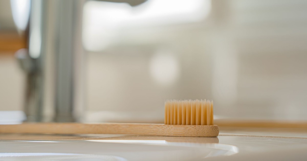 Close-up of a bamboo toothbrush on a bathroom sink showcasing eco-friendly oral care.