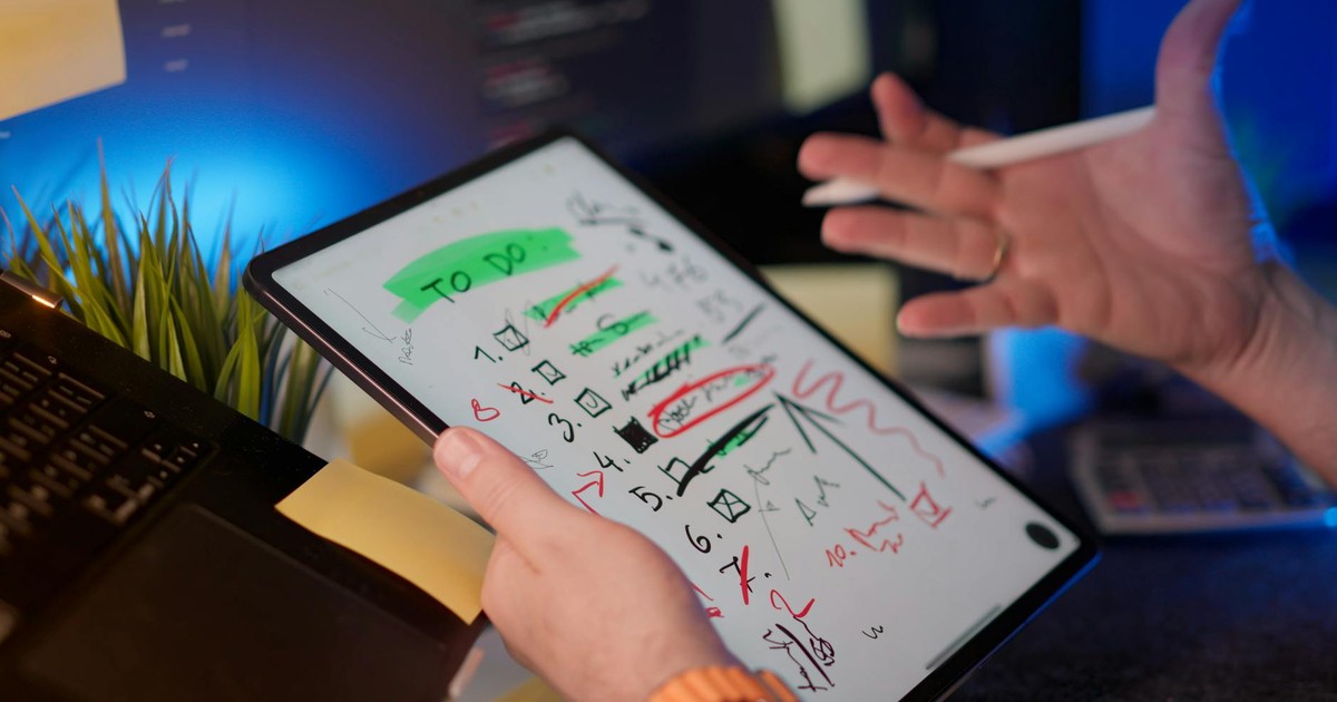 A person managing tasks on a tablet with a digital pen in a modern office setting.