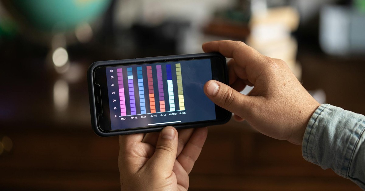 Close-up of hands holding a smartphone displaying a colorful bar graph. Perfect for business and technology themes.