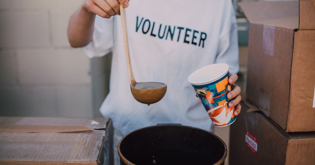 A volunteer in a t-shirt serving soup at a community event. Helping hand.