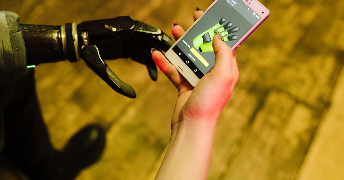 A close-up of a prosthetic hand interacting with a smartphone showcasing futuristic technology.