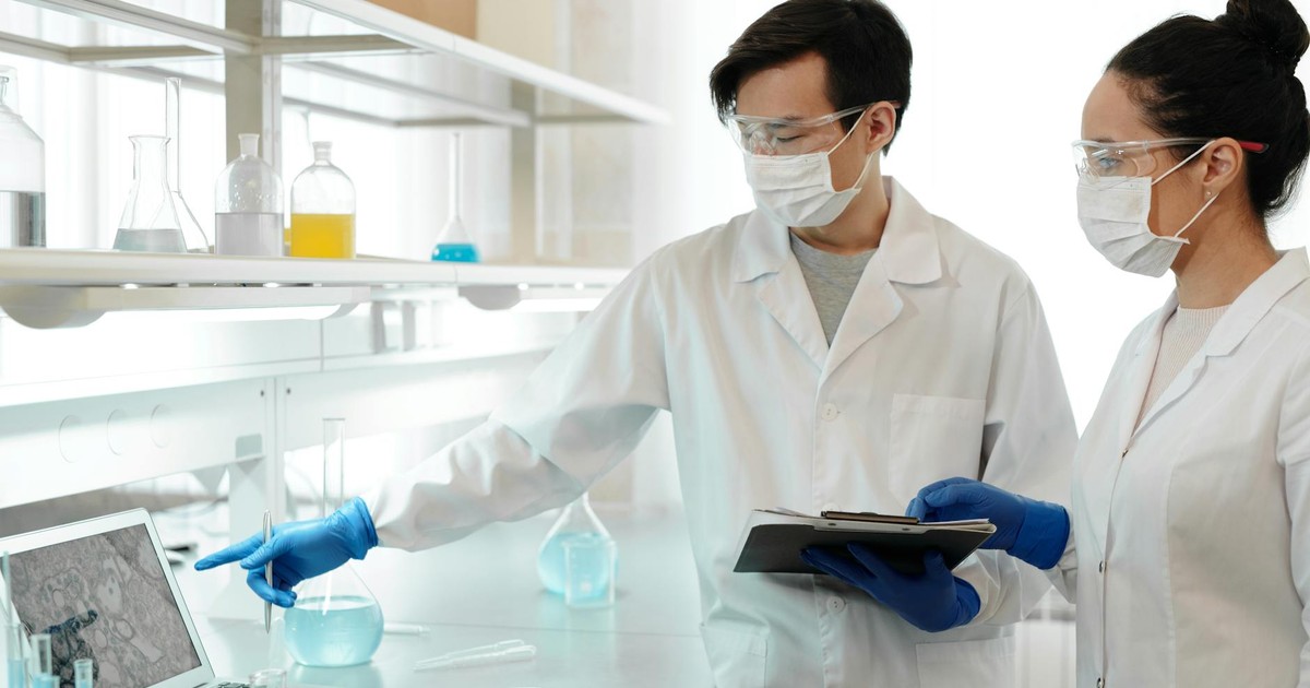 Two scientists in lab coats examining data on a computer in a research laboratory.