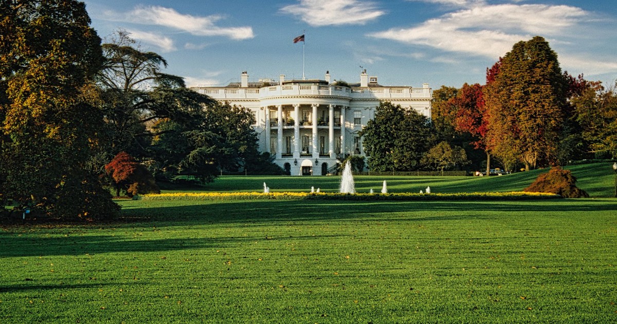 A view of the White House surrounded by autumn foliage and a central fountain in Washington, DC.