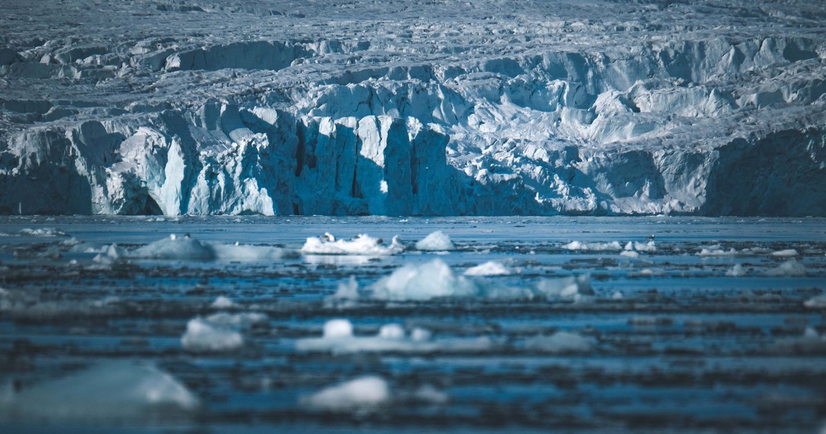 A stunning view of Arctic icebergs floating in the sea against a massive glacier backdrop.