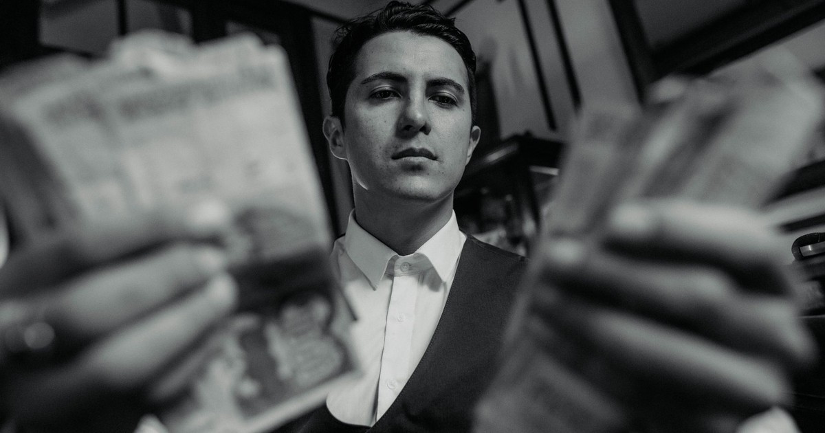 Black and white image of a man in a vest holding cash, exuding wealth and sophistication in Buenos Aires.
