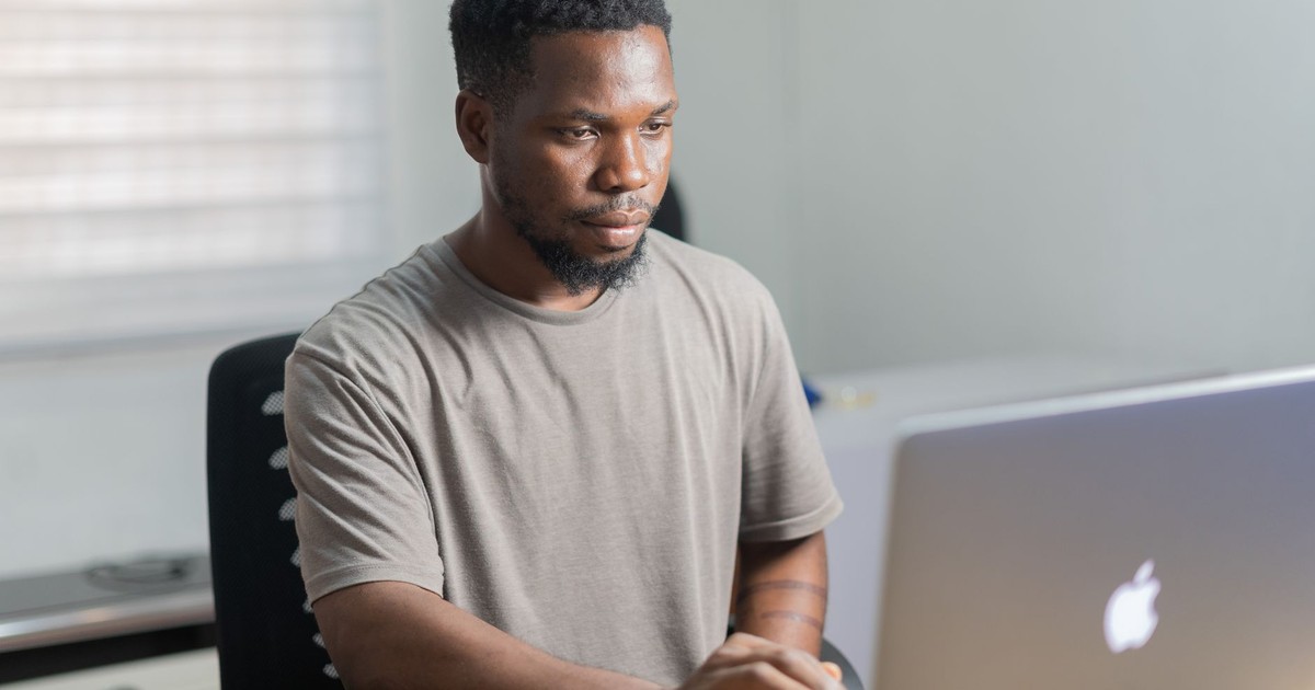 African American man working remotely on a laptop in a well-lit indoor setting.