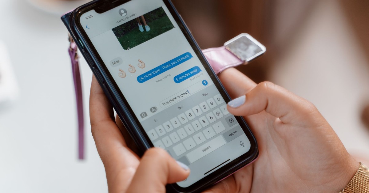 Woman typing on a smartphone, sending a text message with emoji.