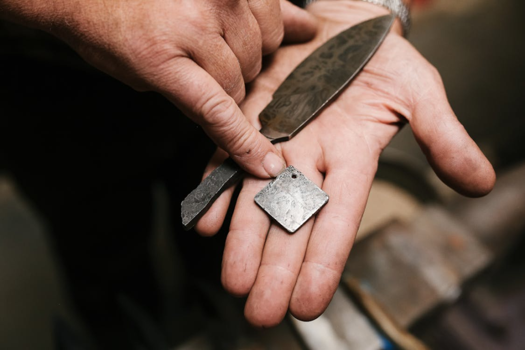 Detailed image showing hands holding intricately crafted metalwork and knife blade