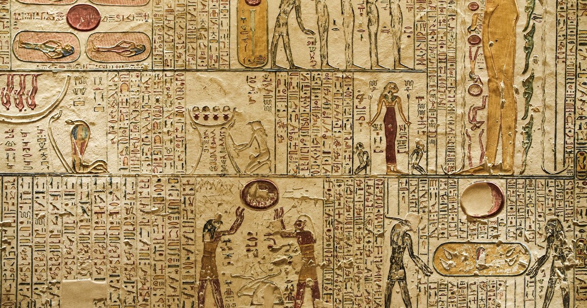 Detailed ancient Egyptian hieroglyphics and figures carved on a temple wall.