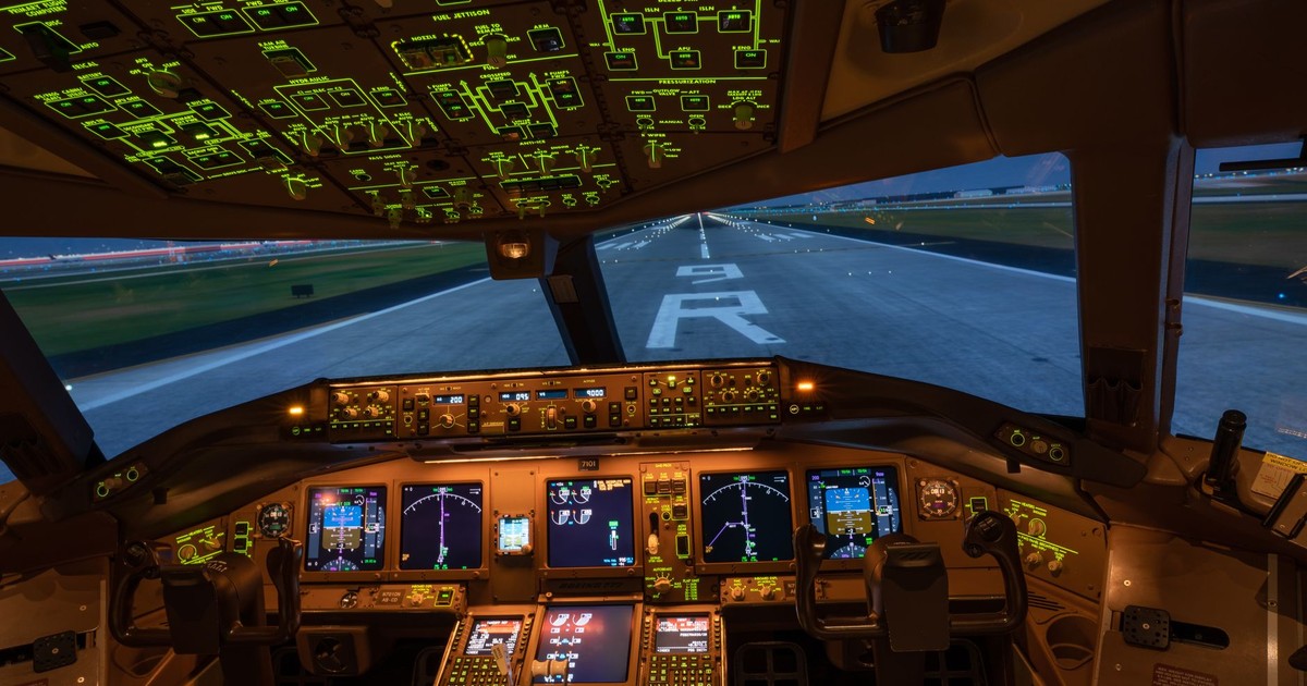 Night view of illuminated airplane cockpit with runway visible, showcasing advanced avionics.