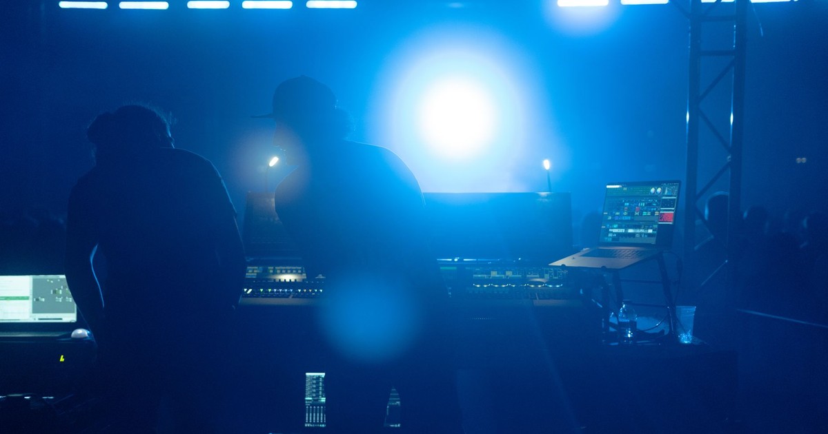 Silhouetted sound engineers working at concert in İstanbul, capturing the vibrant nightlife atmosphere.