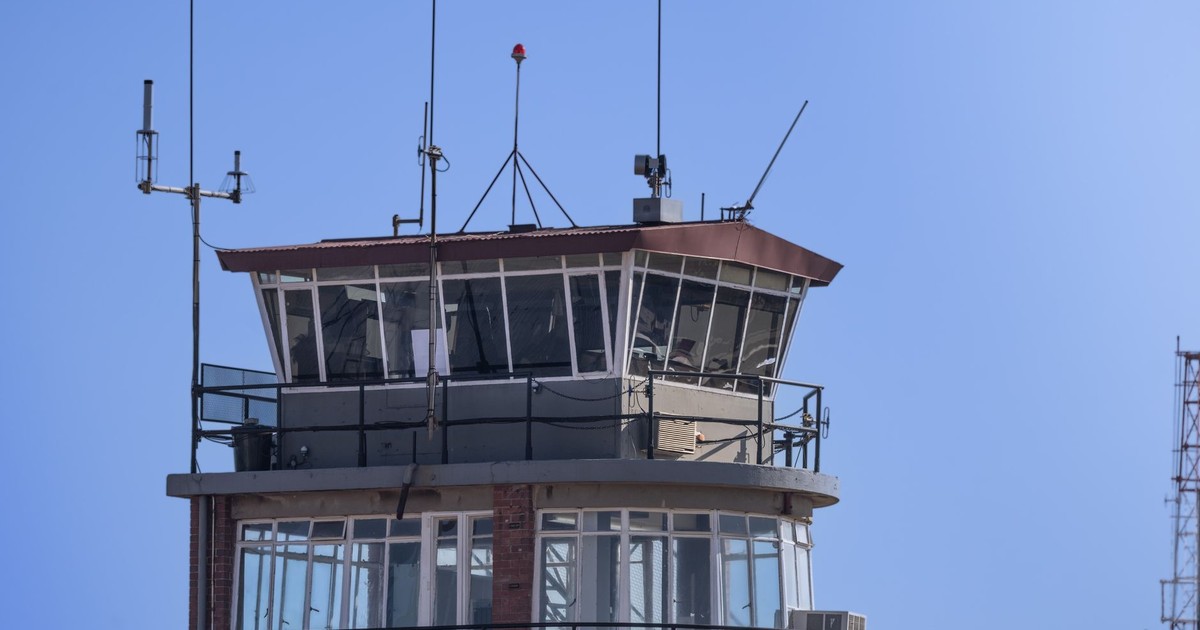 A modern airport control tower against a clear blue sky, showcasing aerial communication infrastructure.