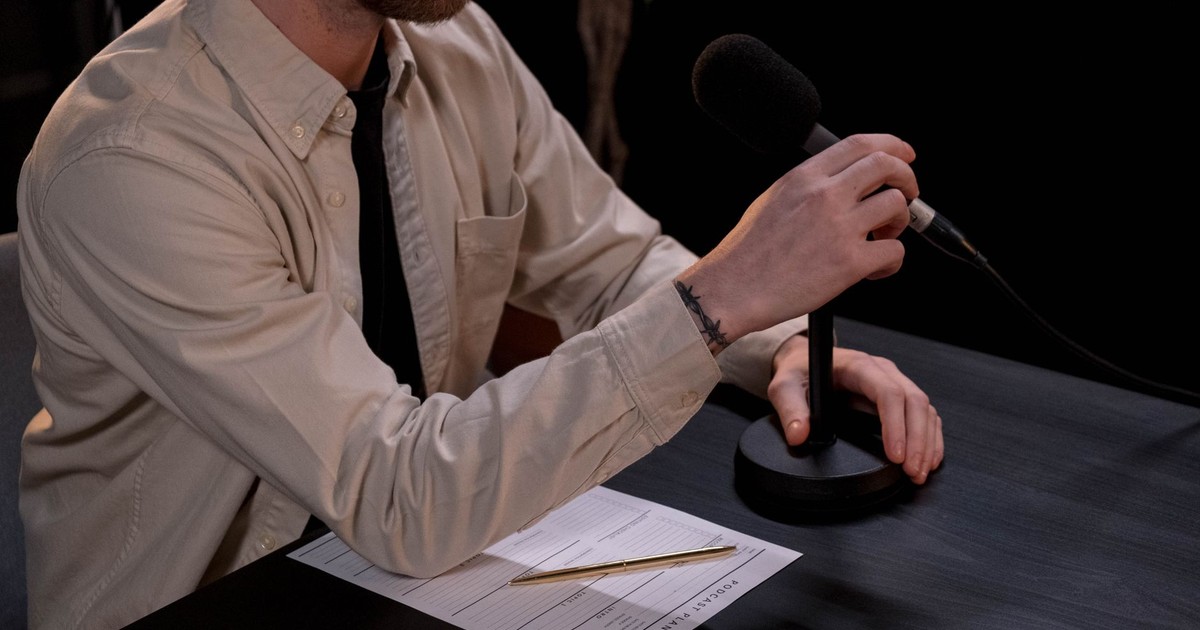 A man prepares for a podcast in a studio with a microphone and notes.