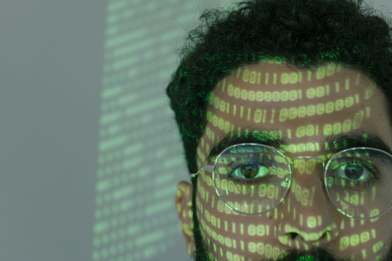 Close-up of a man with binary code projected on his face, symbolizing cybersecurity