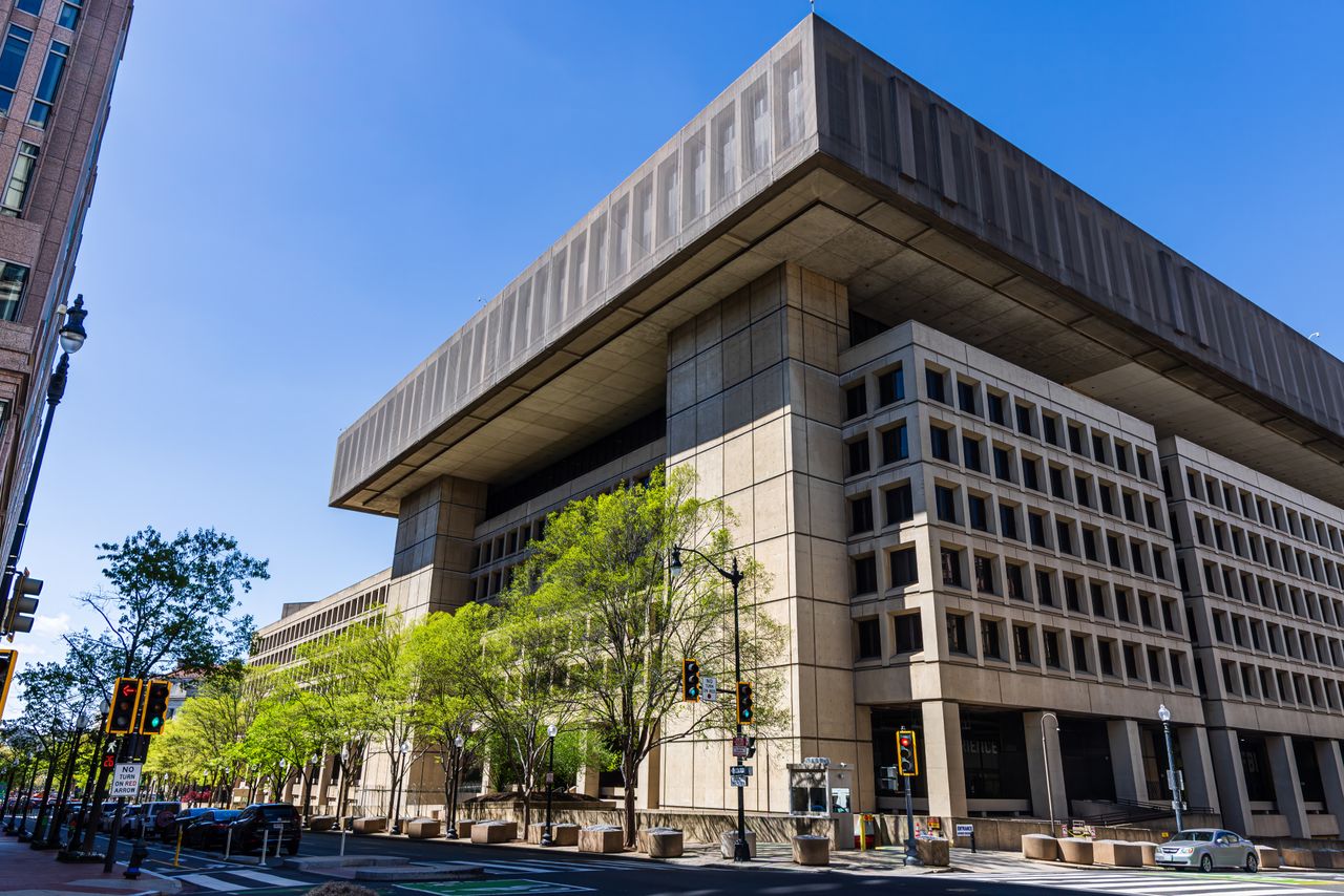 Photo of a modernist government building with a distinct overhang, taken on a sunny day with clear blue skies