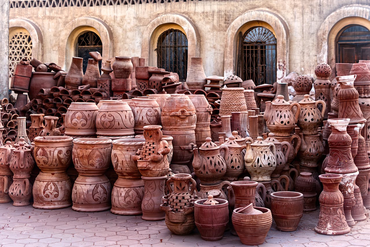 A diverse collection of traditional handmade pottery displayed outdoors, showcasing various styles and craftsmanship