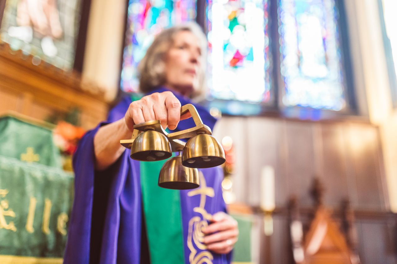 A priest holding altar bells during a religious ceremony in a church