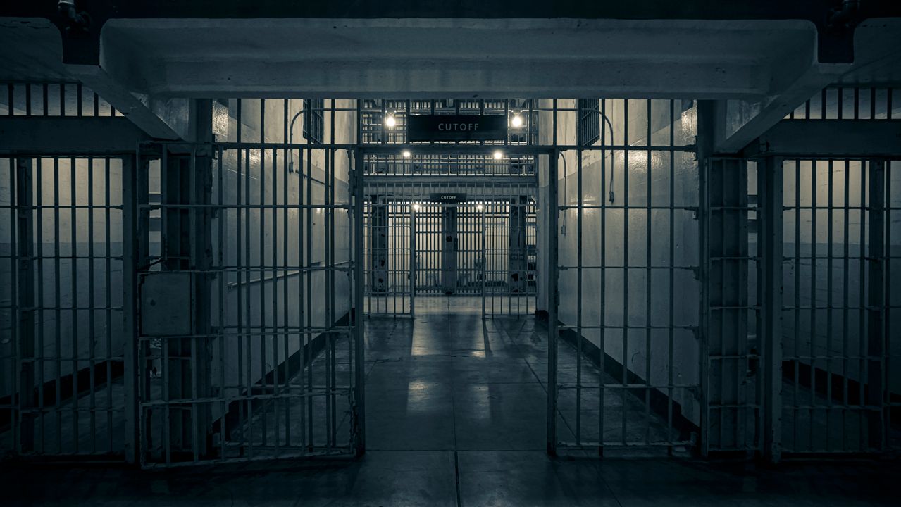 Moody interior of a prison corridor with metal bars, evoking a sense of confinement