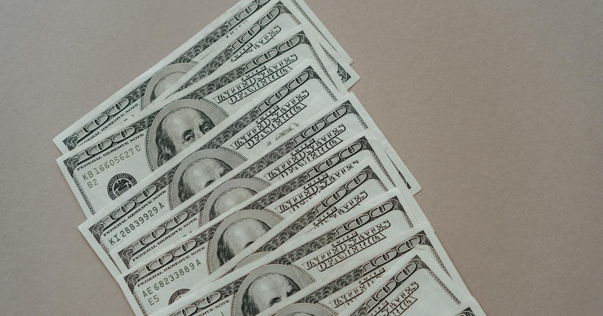 A close-up of multiple US dollar bills arranged on a neutral surface.