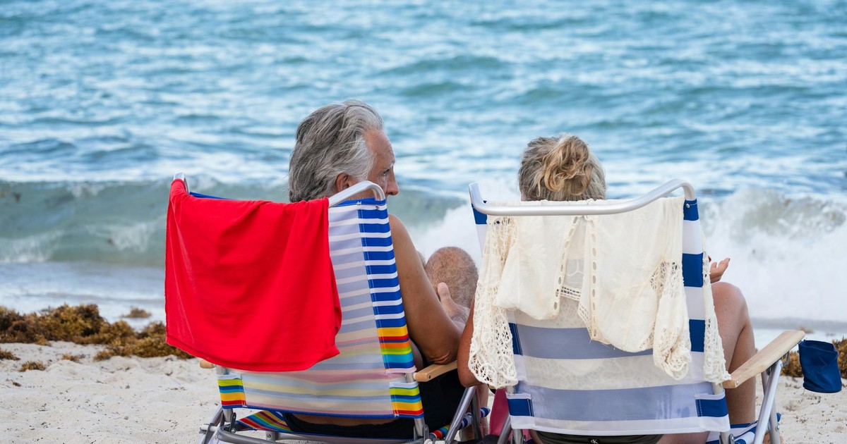 Senior couple relaxing on Miami Beach, enjoying the ocean view and summer sunshine.