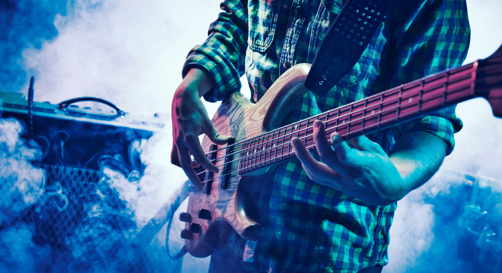 Performance of the rock band. The guitarist plays solo. The bass player plays solo. Drummer. Bass drum. Close-up.