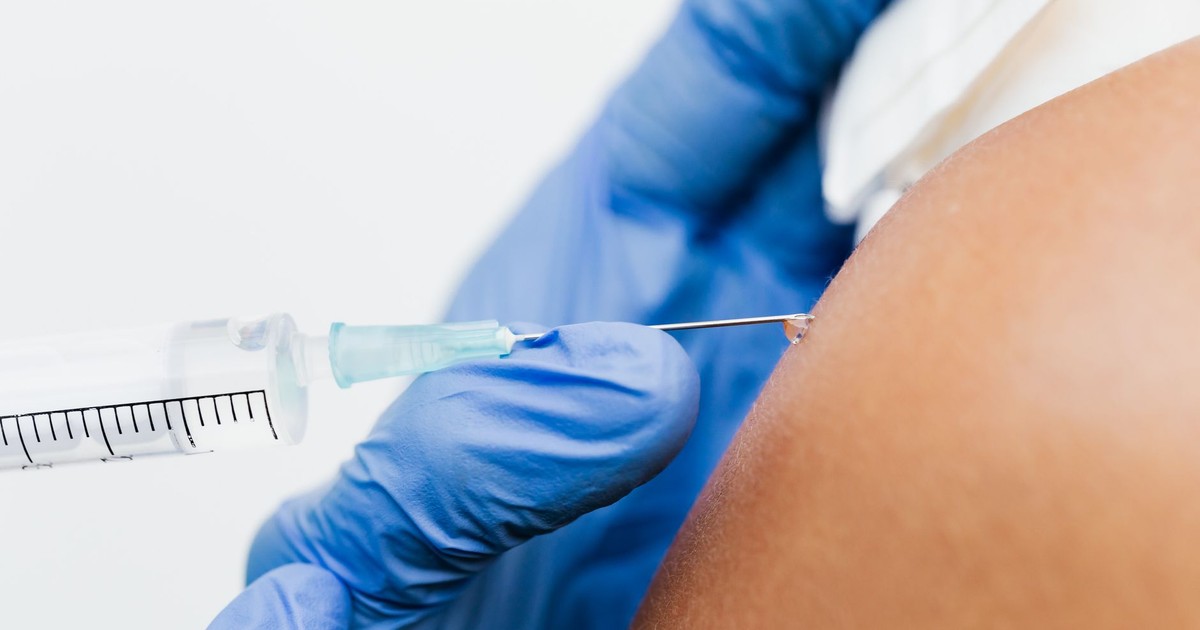 A healthcare professional administers a vaccine using a syringe in a close-up shot.