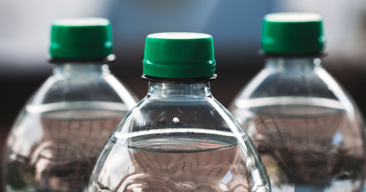 Focused view of three clear plastic bottles with green caps outdoors.