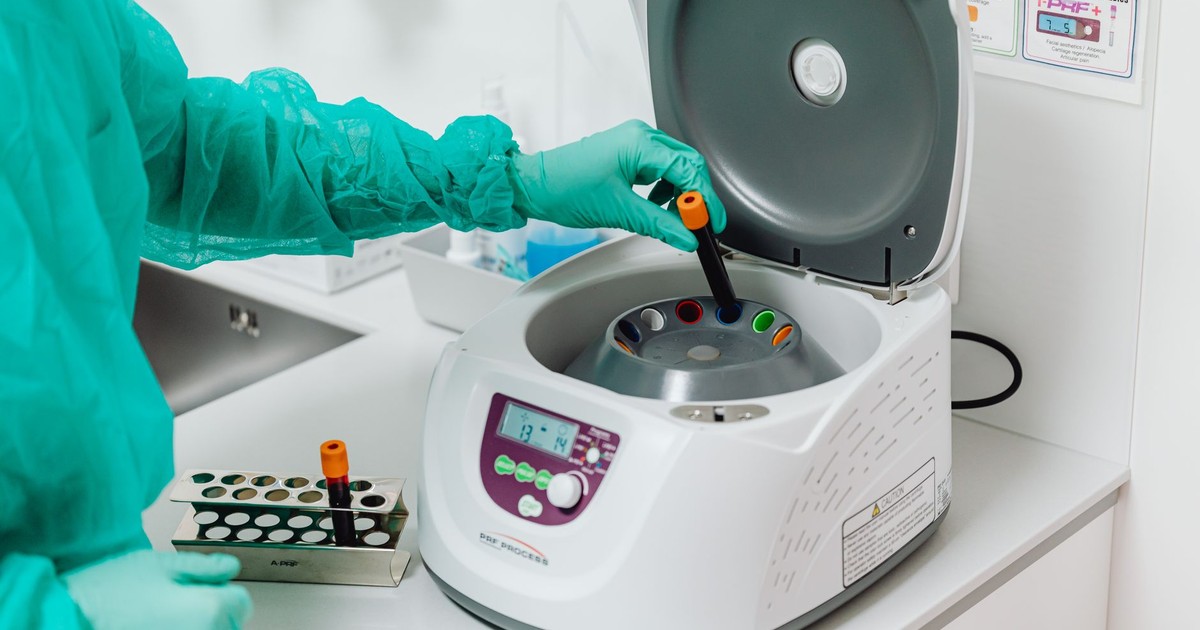 A healthcare professional operates a centrifuge machine in a laboratory, ensuring sterile medical procedures.