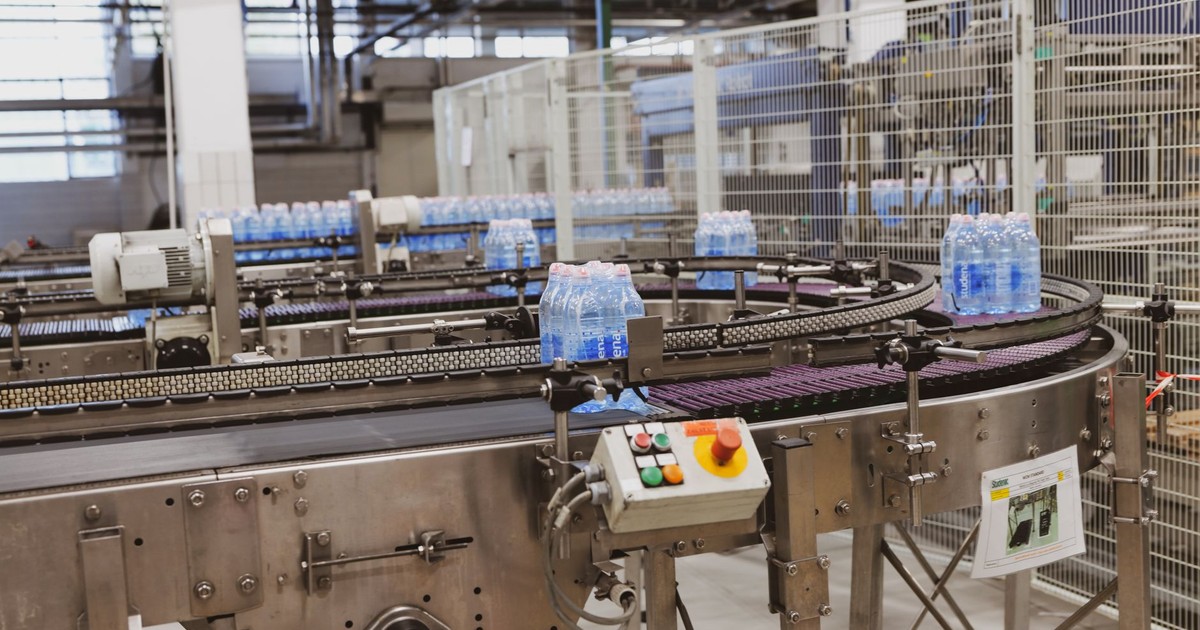 Water bottles being processed on an automated conveyor in a modern factory setting.