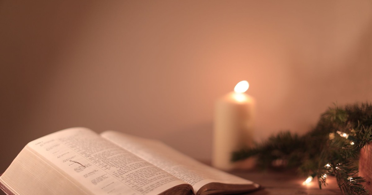 Open Bible with candle and festive greenery creates a serene ambiance.