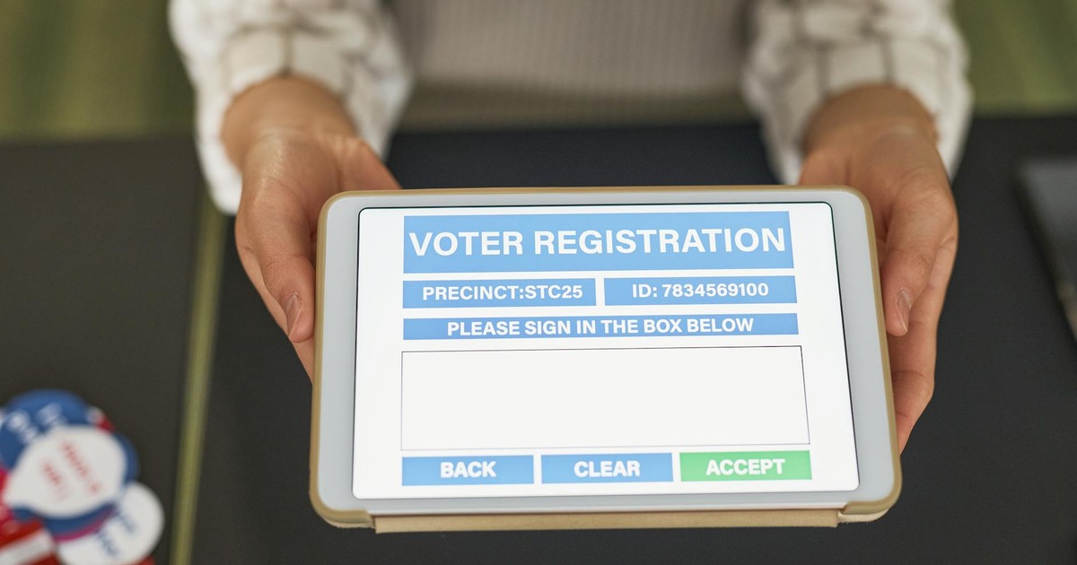 Close-up of hands holding a tablet displaying digital voter registration form.