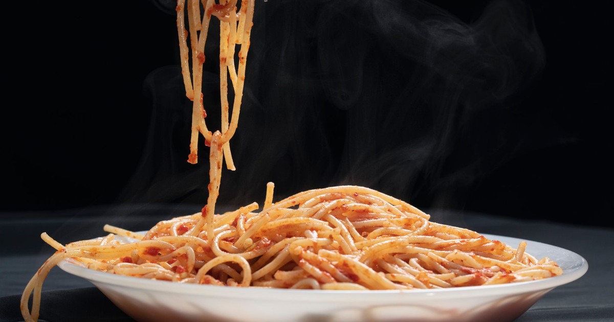Hot spaghetti with rich tomato sauce twirled on a fork, exuding delicious aroma.