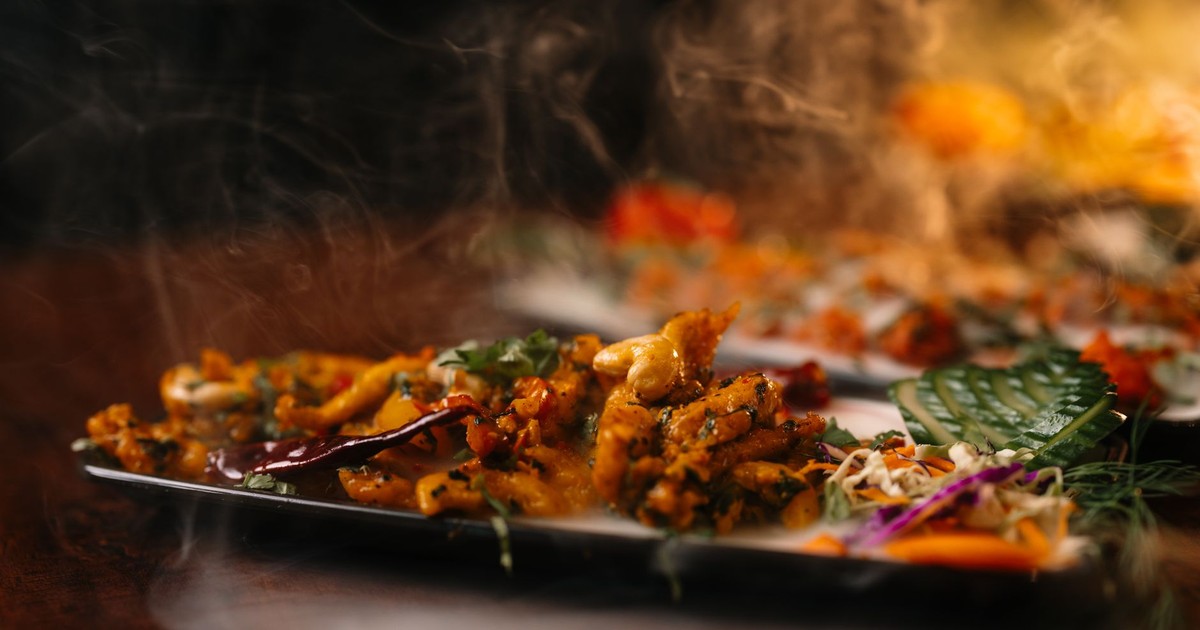 Close-up of a steaming hot Asian dish served in a stylish restaurant setting, highlighting vibrant ingredients.