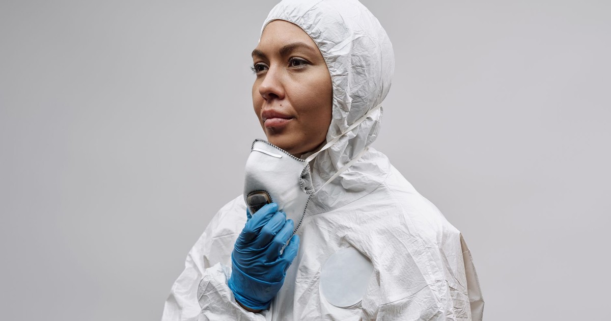 A healthcare worker wearing protective gear and holding a mask. Ideal for clinical and medical themes.
