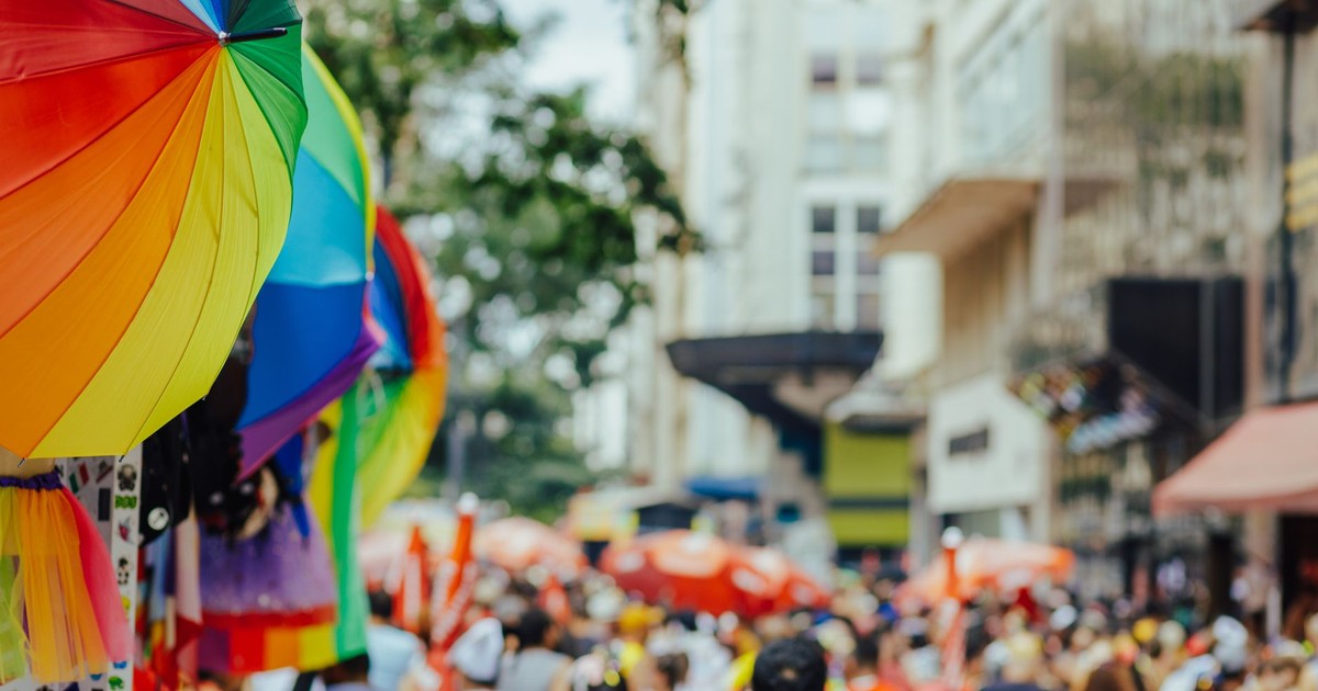 Colorful rainbow umbrellas adorn a lively outdoor city festival with a bustling crowd.