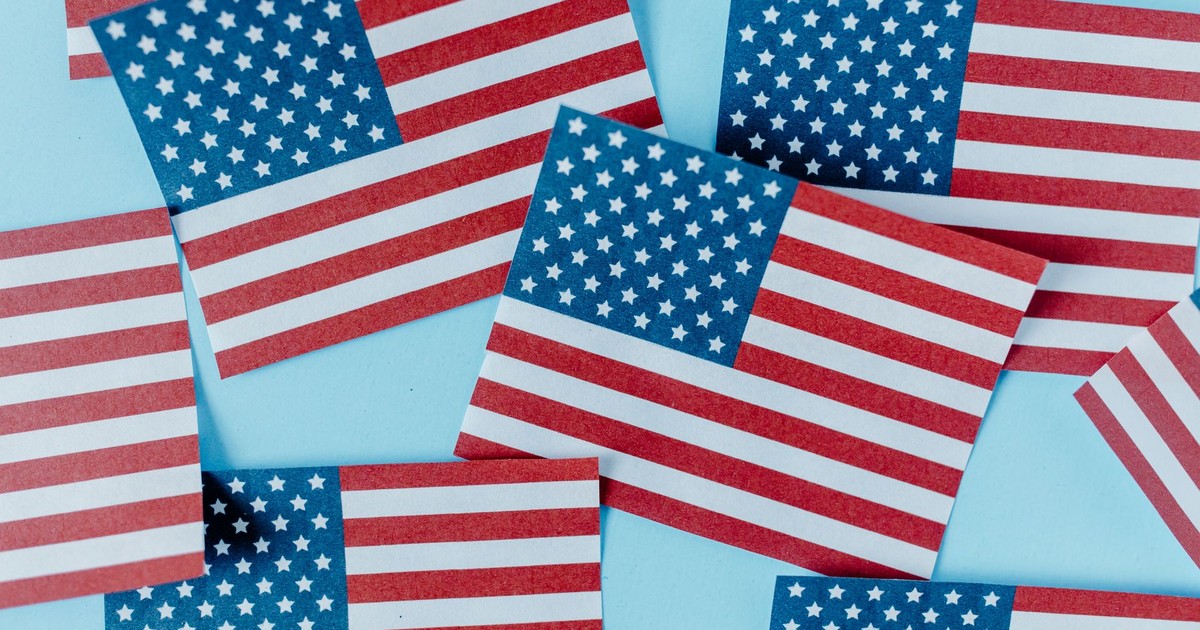 Multiple American flags on blue background symbolizing patriotism and Independence Day.