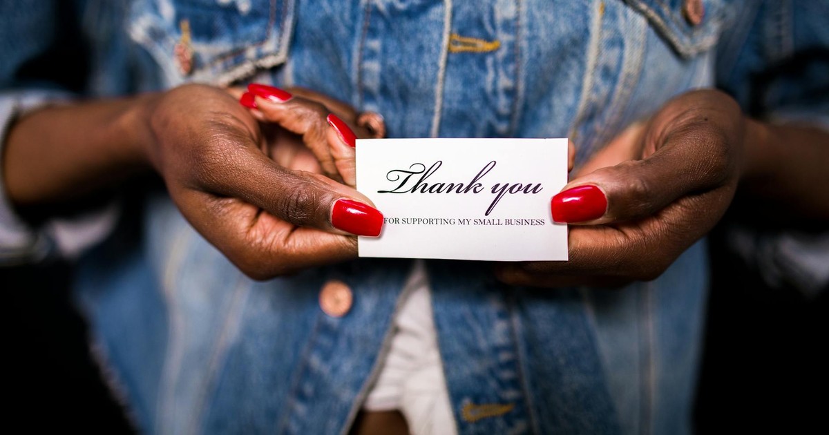 Close-up of hands holding a thank you card supporting small business.