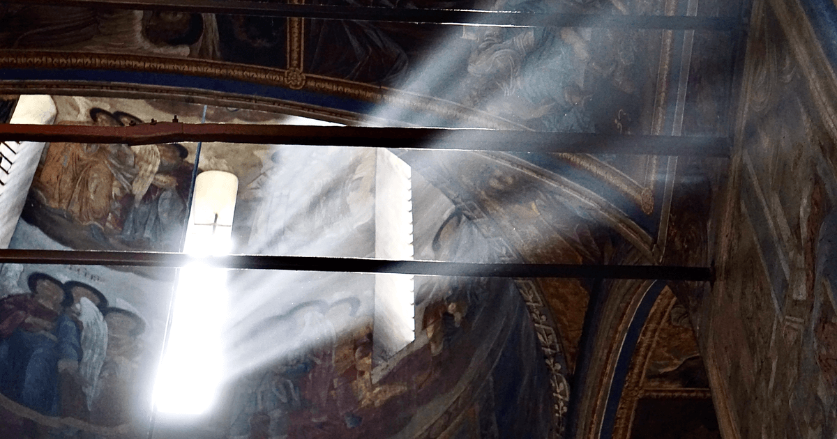 Sunlight beams illuminate the intricate frescoes on a cathedral's ceiling, capturing spiritual ambiance.