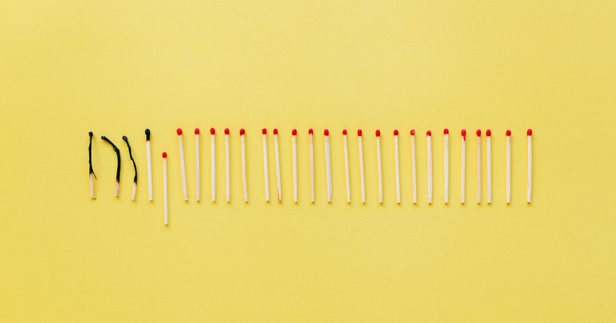 A conceptual still life photo of burnt and unlit matches on a vibrant yellow background.