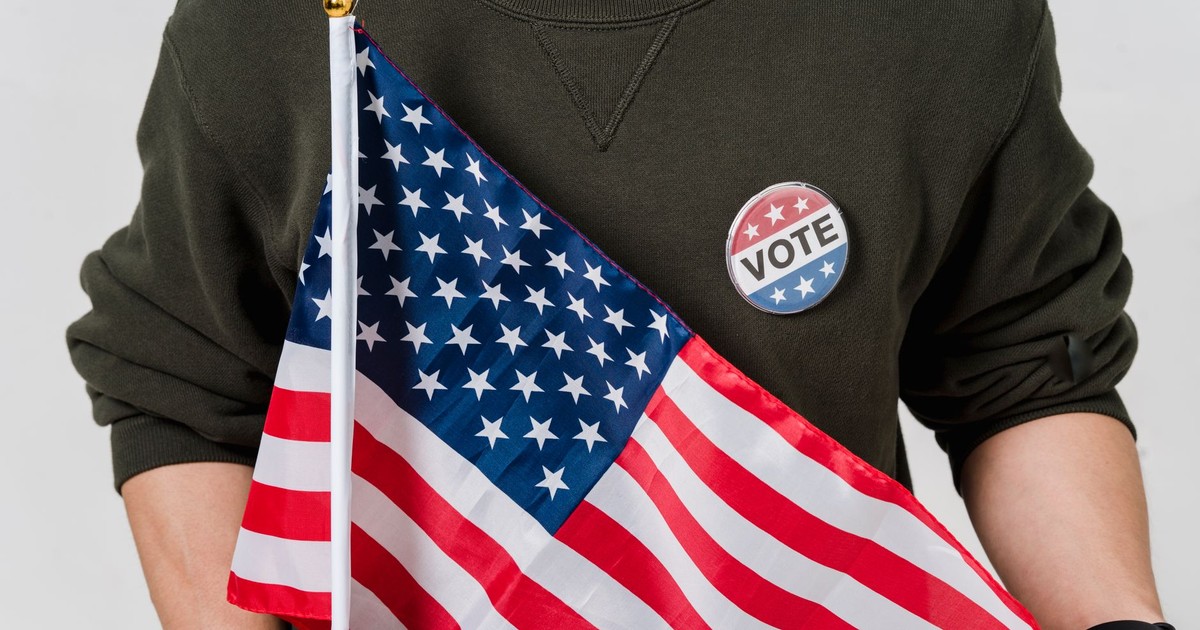 A person holding an American flag with a vote badge, symbolizing patriotism and democracy.