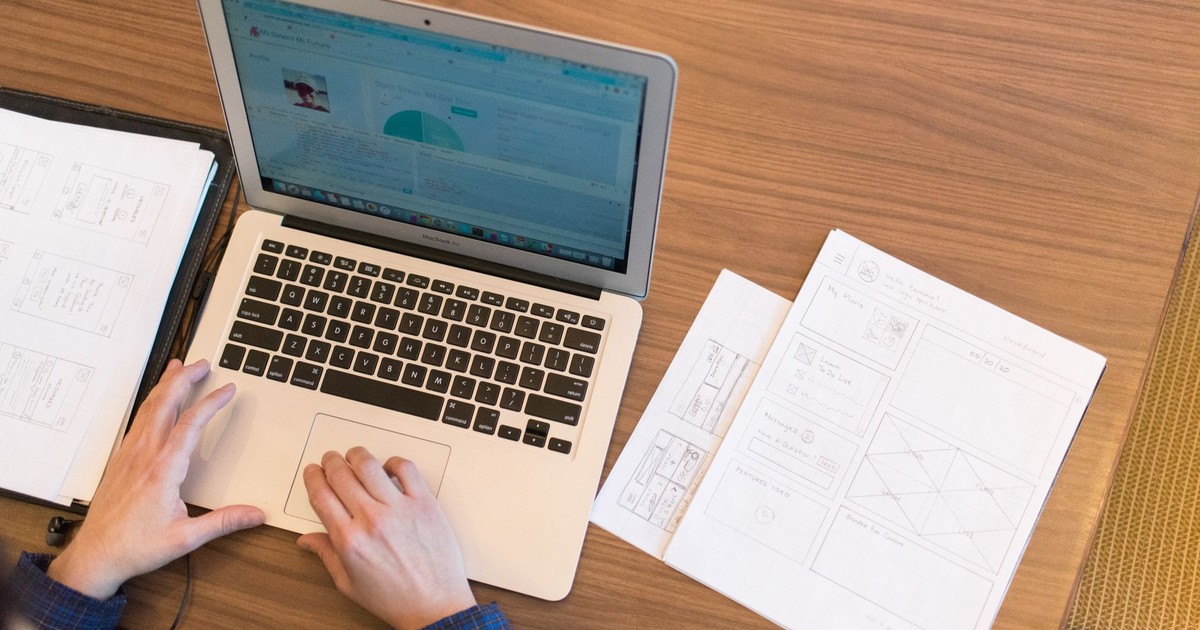 An overhead view of a person working on a laptop at a desk with documents and papers.